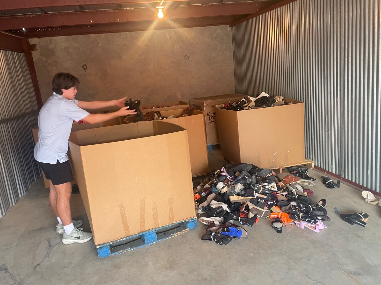 A volunteer sorts donated shoes into bins in our storage unit